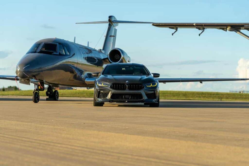 Luxury black car waiting for passengers next to a private jet at Tampa airport.
