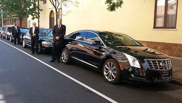 Professional chauffeurs standing beside luxury Cadillac sedans for Bradenton Car Service and executive transportation.