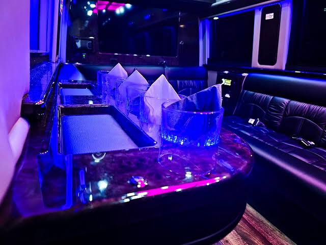 Luxury party bus interior for Bachelor Party Limo Service with premium leather seating, ambient LED lighting, and elegant table setup.
